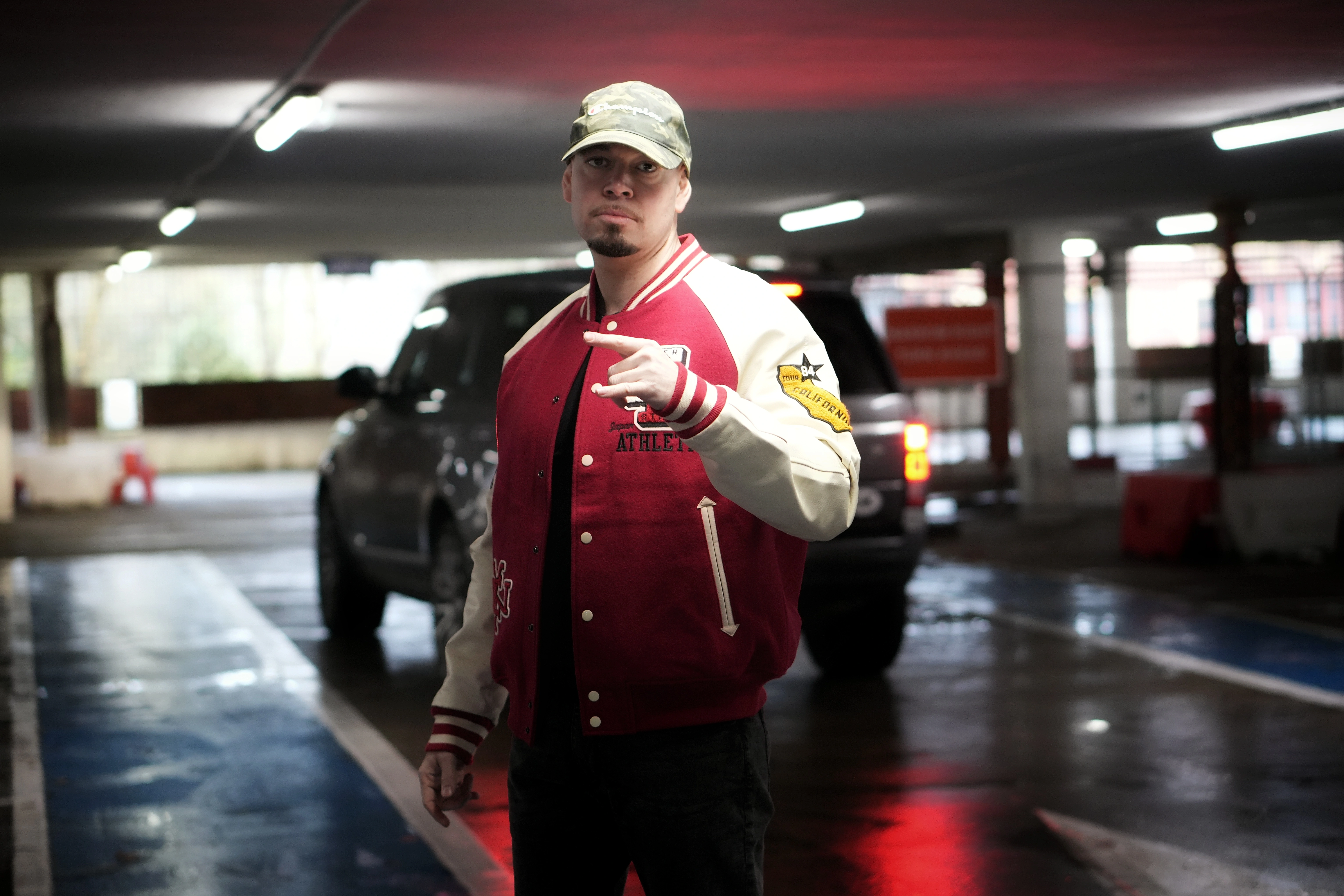 Person in black bucket hat and patterned shirt preparing to take a pool shot