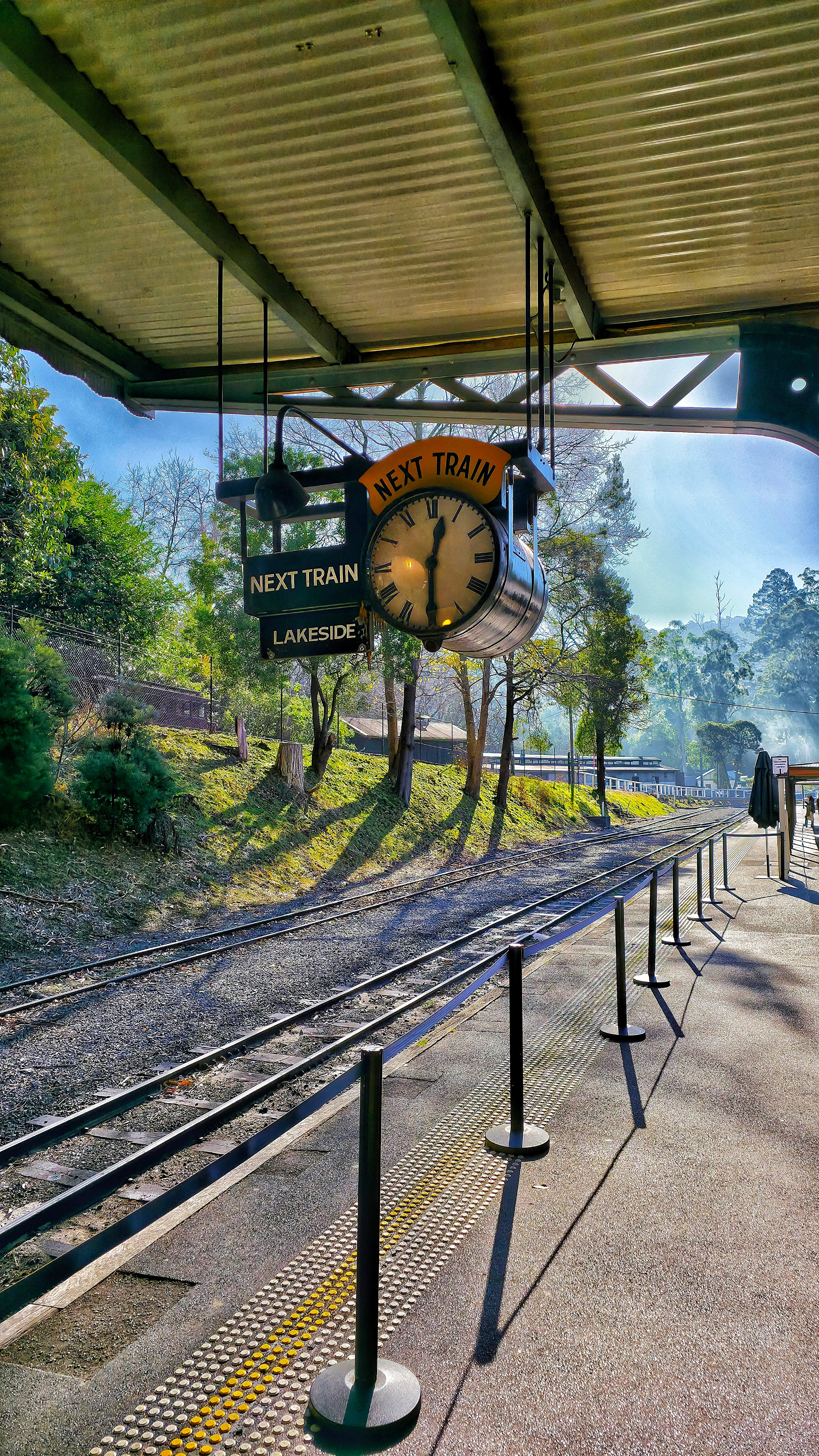 Sunset over a tranquil lake with rocky shoreline and distant hills