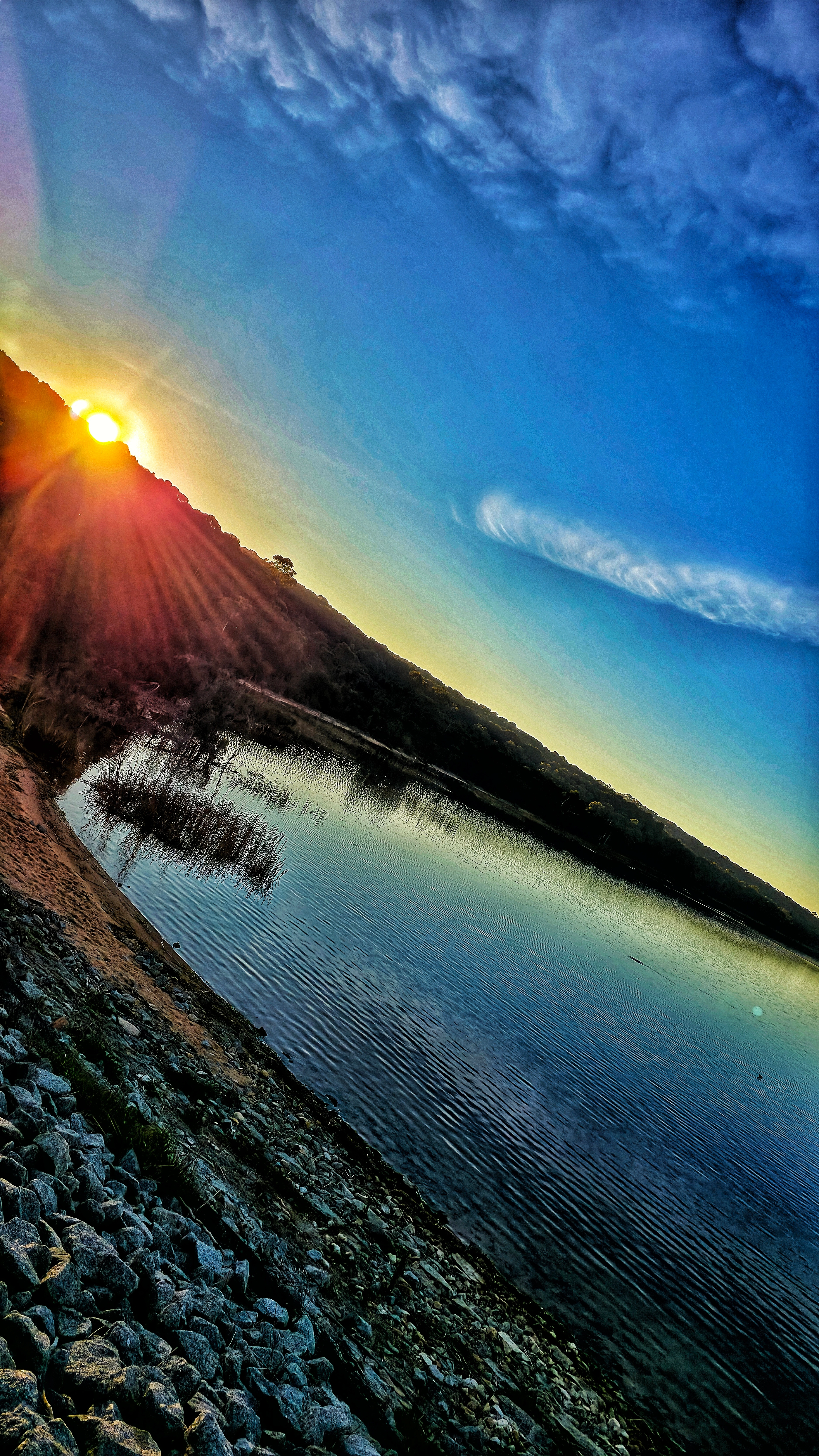 Ocean wave splashing against the shore with sun shining through water droplets and blue sky