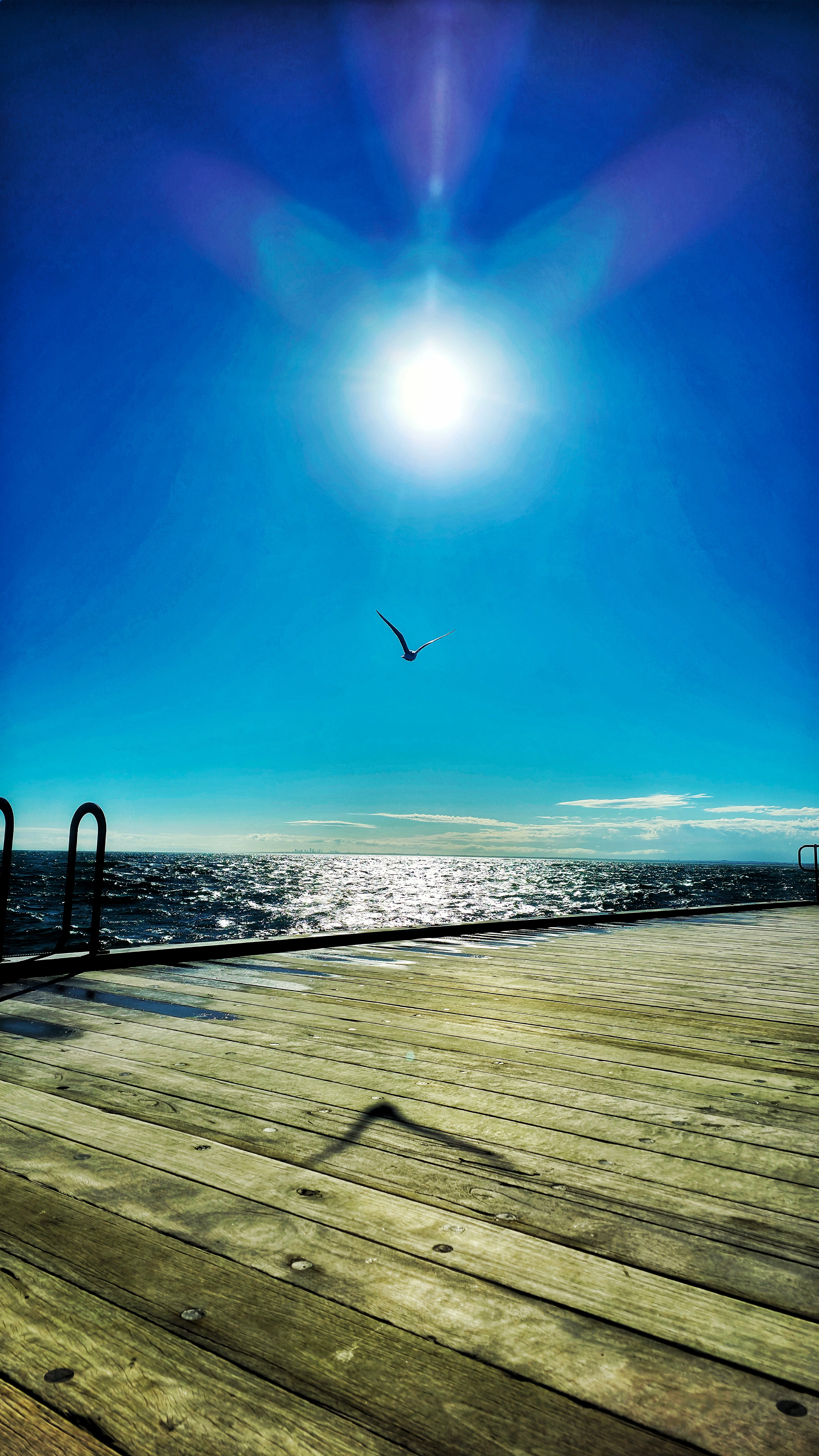 Tilted aerial view of dramatic coastal cliffs with golden rock layers and turquoise ocean waves
